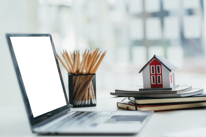 house-model-with-laptop-on-table-of-real-estate-ag-2023-11-27-05-23-46-utc 1